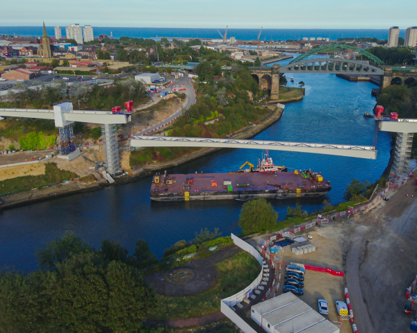 A barge on a river going under a bridge. 