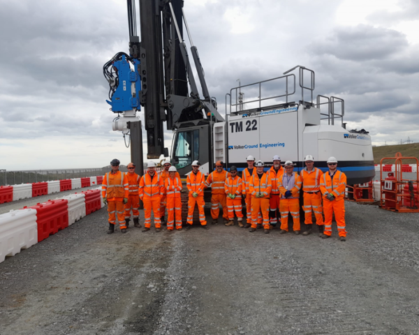Picture of men in high vis stood in front of a piling rig.